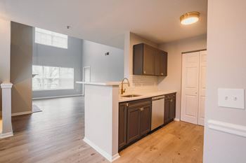 an empty kitchen with a white counter top and a door to a living room
